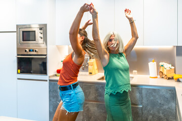 Joyful women dancing together in modern kitchen