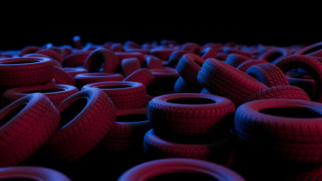 Numerous car tires are illuminated by red and blue neon lights, creating an abstract and thought provoking scene related to tire recycling, waste management, and environmental conservation