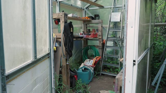 Serre avec plein d'outils de jardinage en d&eacute;sordre 