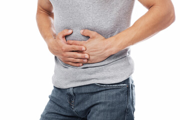 Cropped millennial european male suffering from abdominal pain and pressing his hands to sore spot,...
