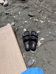 slippers on a black beach