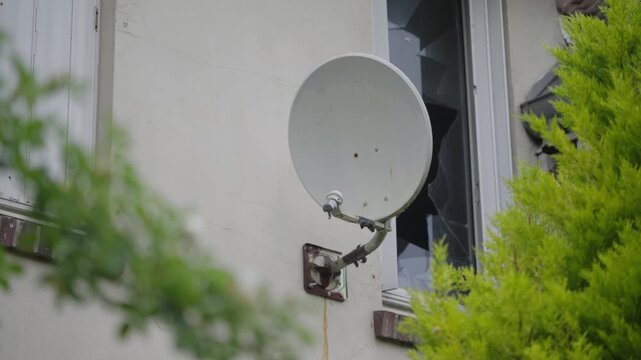 Parabole sur la fa&ccedil;ade d'une maison abandonn&eacute;e avec une fen&ecirc;tre bris&eacute;e 