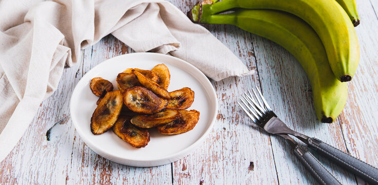 Fried plantain banana slices on a plate on the table web banner