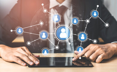 A businessman interacts with a tablet, visualizing a digital network of professionals in a modern office. The image illustrates technology, communication, and business connections. Tessel