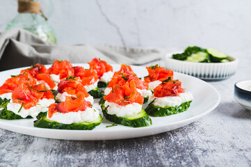 Appetizing snack of cucumber, ricotta and red fish on a plate on the table