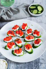 Cucumber appetizer with ricotta and salted red fish on a plate on the table vertical view