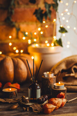 Cozy interior with knitting, burning candles and aroma perfume diffuser in the living room. Fall...