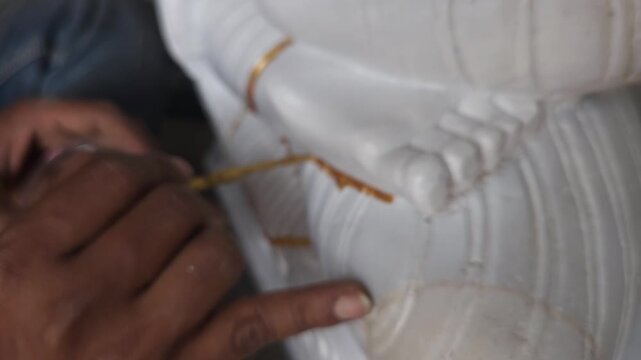 Hand of an artist doing paint on statue