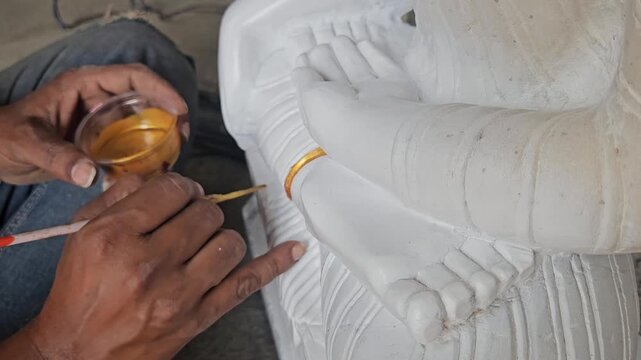 Hand of an artist doing paint on statue
