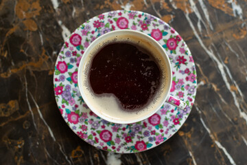 Top-down view of an aromatic coffee cup with floral pink service set on a dark marble table, perfect for elegance. Ideal for food visuals, home decor, or luxury lifestyle content with a chic appeal.