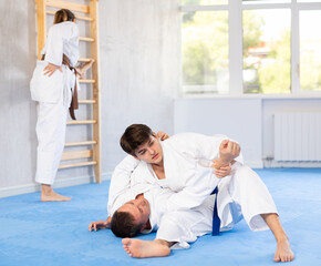 Athletes in white kimonos practice Brazilian jiu Jitsu Aikido Wing chun wrestling. Training at...