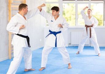 Naklejka premium Two men are trained to perform basic defensive karate installations and attacking actions for combat techniques classes. Coach comments and corrects mistakes of students