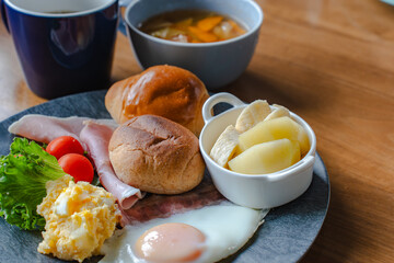 Western style breakfast with bread, fried egg, ham, salad, banana, and coffee
