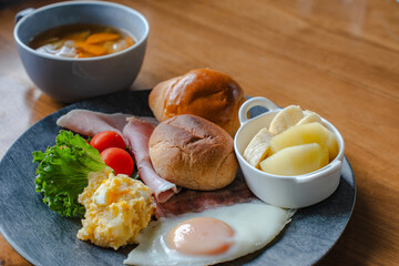 Western style breakfast with bread, fried egg, ham, salad, banana, and coffee
