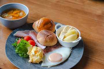 Western style breakfast with bread, fried egg, ham, salad, banana, and coffee
