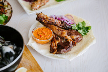 Grilled lamb ribs with red onion, herbs and spicy sauce on lavash flatbread