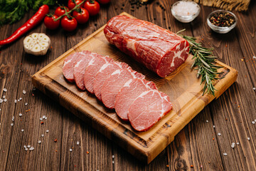 Fresh raw pork loin with rosemary on a wooden cutting board, perfect for cooking or grilling recipes