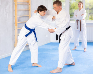 Obraz premium Male athletes in pair conduct training battle in oriental fighting technique under guidance of female coach and mentor. School of martial arts. Strengthening strength of mind and body