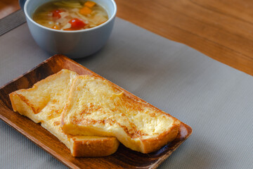 French toast breakfast with soup on wooden plate
