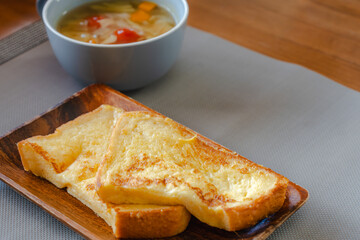 French toast breakfast with soup on wooden plate
