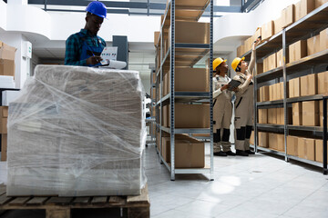 Staff performing manual labor tasks in a busy industrial warehouse, managing product dispatch, checking orders and organizing cargo for shipment in the logistics center activity.