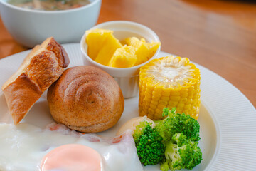Healthy Western breakfast with fried egg, bread, corn, broccoli and pineapple
