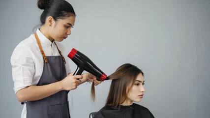 A female hairdresser working on a woman's hair with a blow dryer