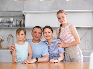 Young family with preschool children sitting at kitchen table. Married couple sitting near desk...