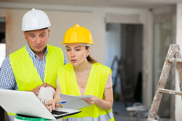 Fototapeta premium Woman architect and man engineer discussing reconstruction project in apartment, using laptop.