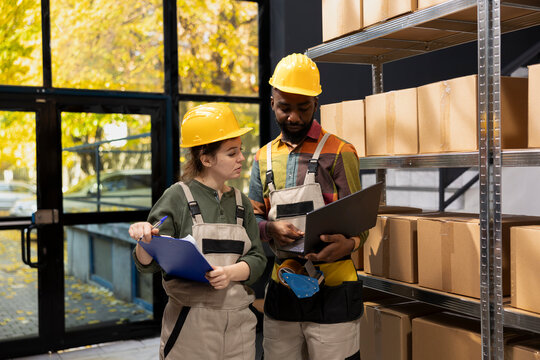 Diverse workers team ensuring accurate inventory in a small scale warehouse, managing cardboard boxes for e-business delivery, wholesale shipments and retail product distribution. - Powered by Adobe