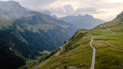 Swiss Alps with houses, winding road, clouds, and overcast sky, captured by drone. Schweizer Alpen...