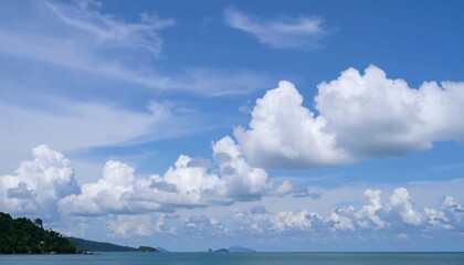 Obraz premium Expansive blue sky, fluffy white clouds, serene ocean