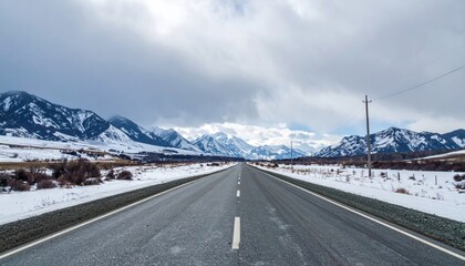 Empty Asphalt Road Leading Towards Snowy Mountains Under Cloudy Sky