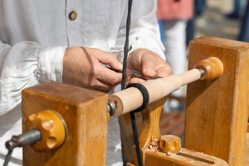 Carpenter using traditional wood lathe shaping wood