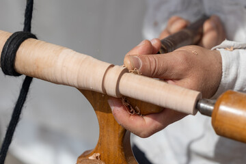 Carpenter using traditional lathe for shaping wood