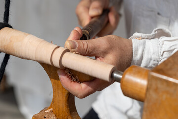 Carpenter turning wood piece with traditional lathe and hand tools