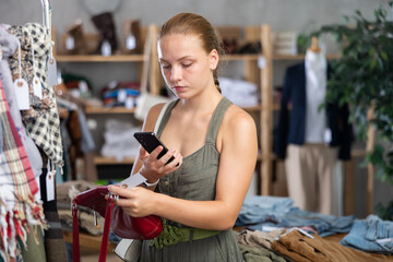 Female shopper scans the barcode of label on bag to view the material information. European woman pays for purchases in the store using a qr code