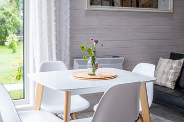 Scandinavian interior design featuring minimalistic dining area with white table, cozy chairs, and natural light, creating a bright and airy atmosphere with functional elements and neutral tones