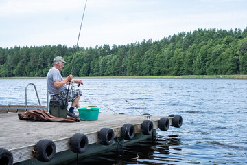 Senior man engaged in fulfilling fishing hobby on a serene dock, surrounded by lush greenery and...