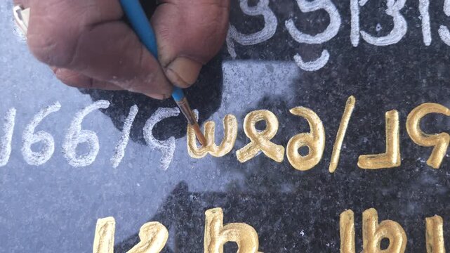 Close Up Of An Indian Sculptor Artist Panting On Engraved Stone