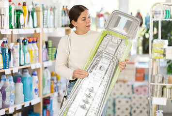 European woman chooses an ironing board in the household section of a hypermarket. Woman choosing...