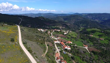 Naklejka premium High-angle view of a village nestled in a valley, surrounded by mountains and farmland