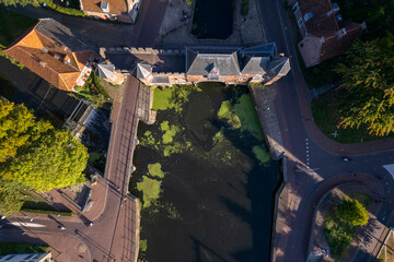 Top down aerial view double gated medieval city entrance Koppelpoort structure in Amersfoort, The Netherlands, with the authentic rooftops of the historic center in the background