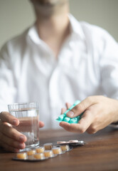 Man in a White Shirt Contemplating with an Hourglass and Medication stress