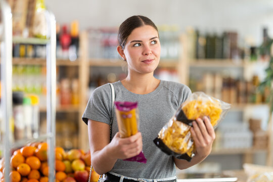 Woman choosing pasta and spaghetti in the supermarket. European woman buying durum wheat pasta in the grocery section - Powered by Adobe