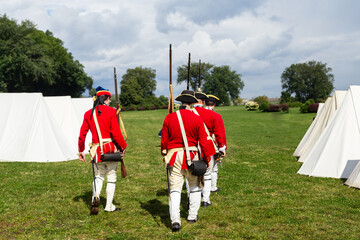 Back view of men in French regimental uniforms marching during a re-enactment of the 1759 battle of...
