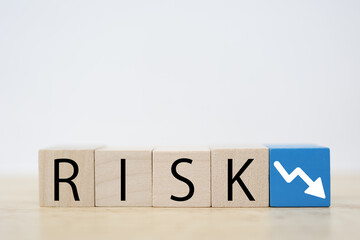 木のブロックにRISKと下向き矢印。リスクと下落概念。