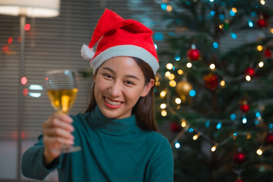 Happy Asian woman wearing santa hat toasting with champagne to celebrate Christmas holiday