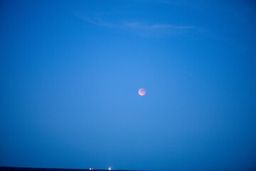 A stunning photo of a lunar eclipse with the moon glowing at night above the sea, creating a dramatic celestial seascape.