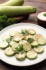Delicious fried courgette slices with parsley, sour cream and fresh vegetables on wooden table,...